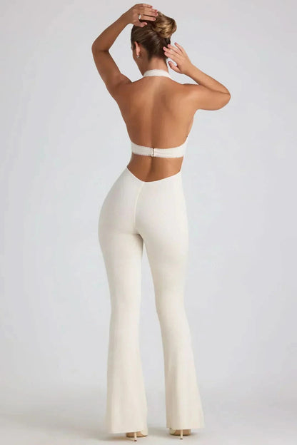 Rear view of white halter jumpsuit with backless cut and flowing flared pants