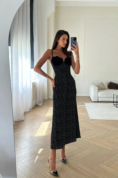 Woman wearing black polka dot midi dress with sweetheart neckline in interior setting
