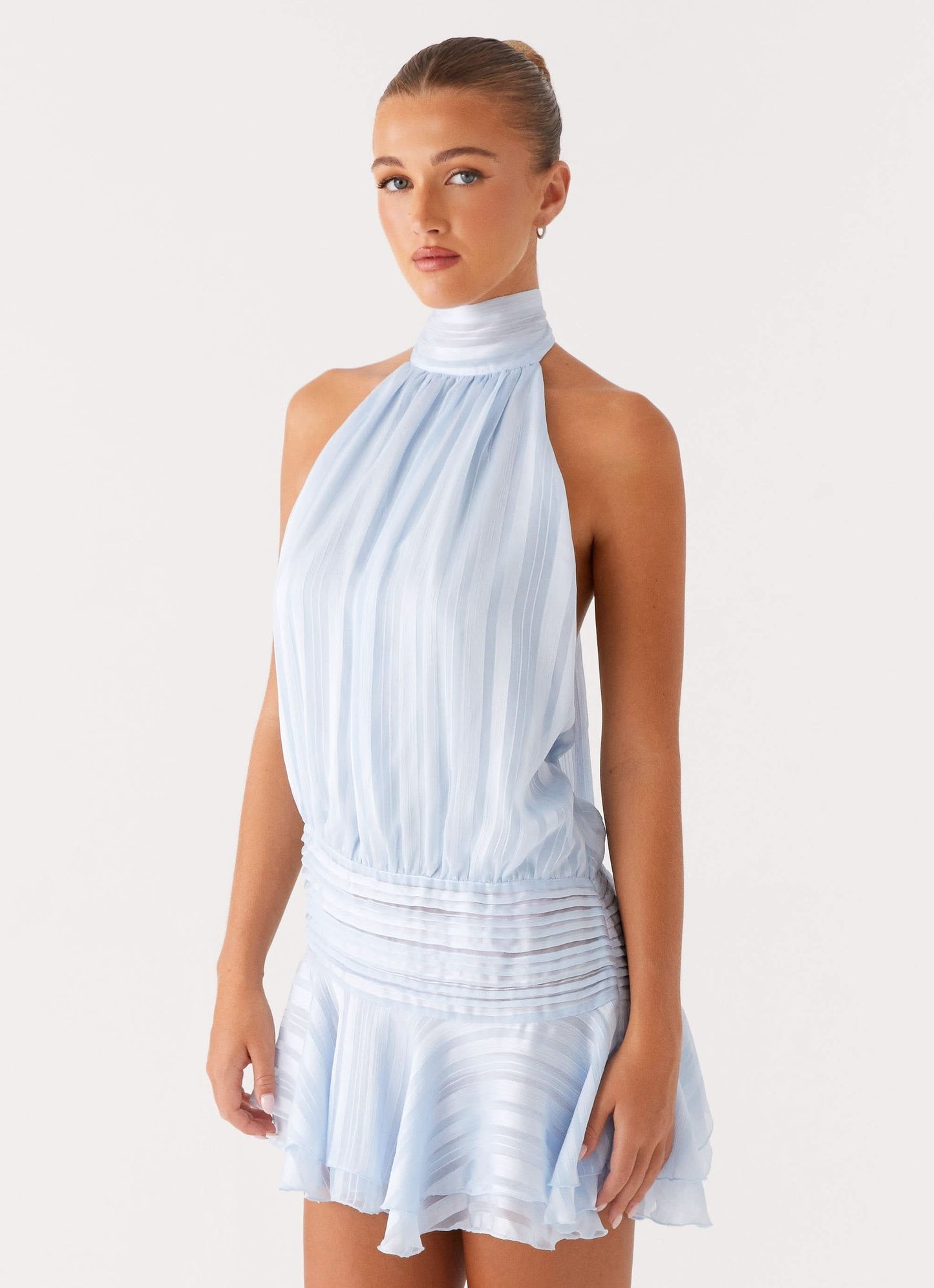 Side angle of light blue halter chiffon mini dress showing pleated fabric and ruched details
