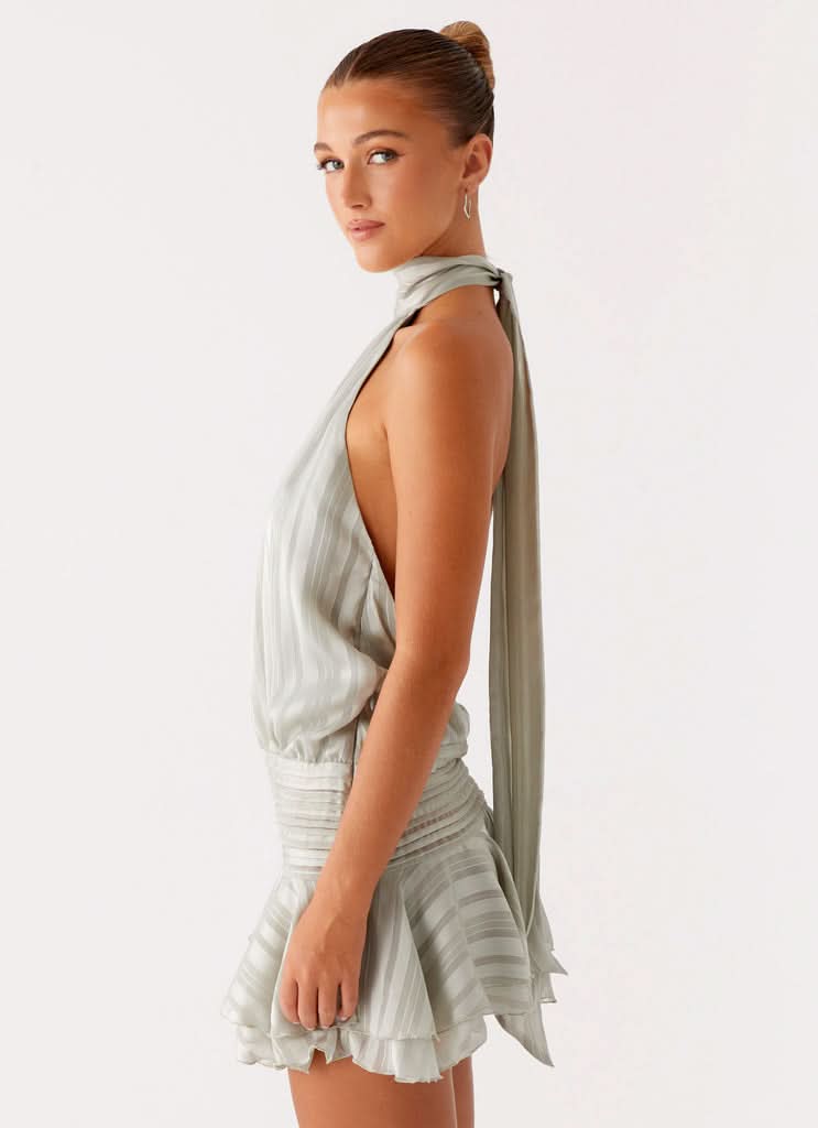 Side angle of sage green chiffon mini dress with open back and long tie detail