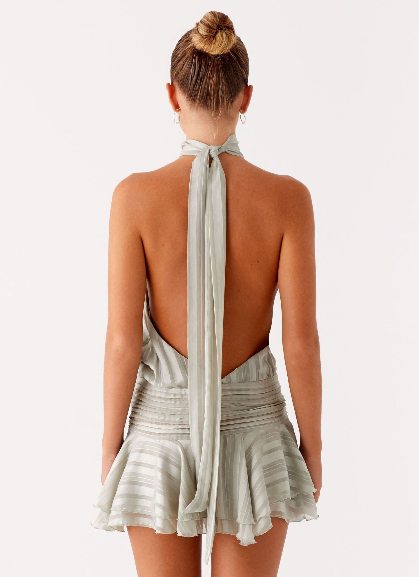 Back view of sage green chiffon mini dress with open back and tied halter closure