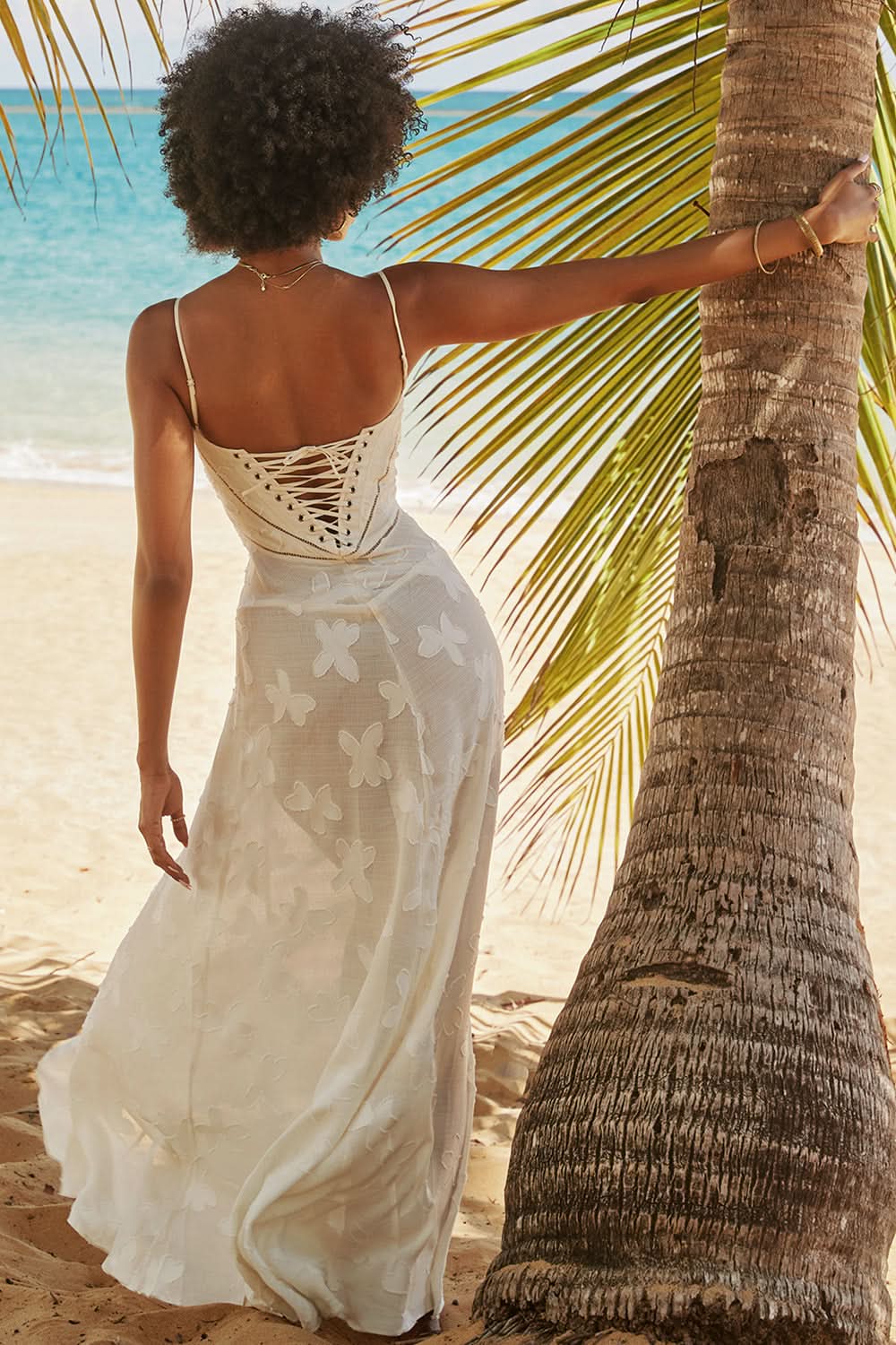 Cream white floral maxi dress with lace-up corset back on beach with palm tree