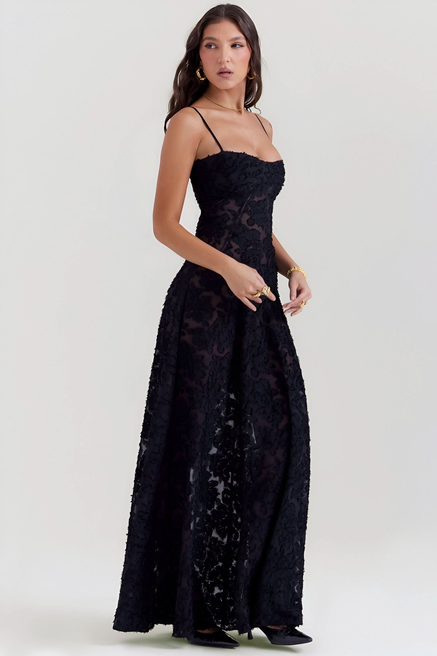 Side view of black lace maxi dress with draped skirt and thin shoulder straps