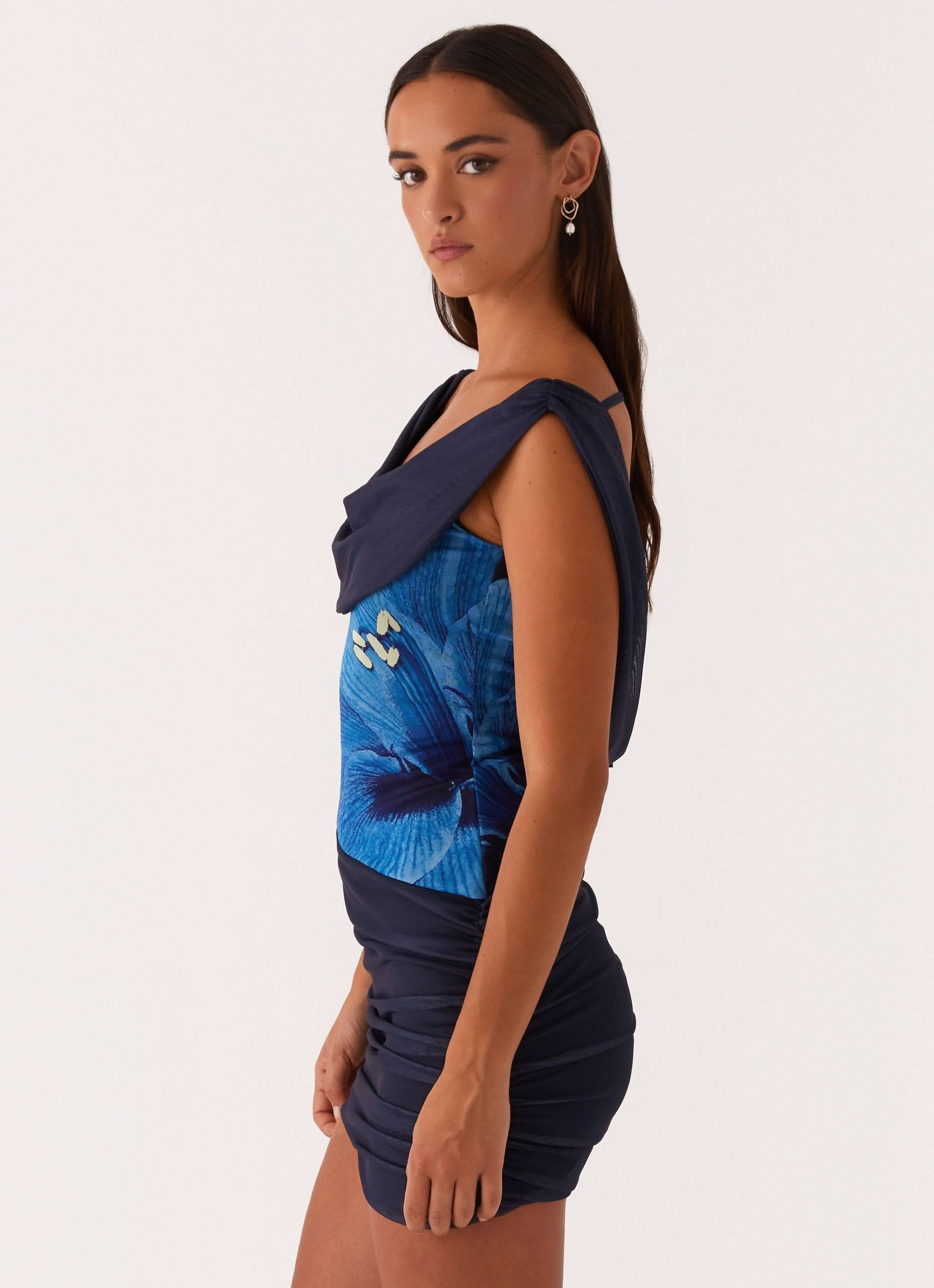 Side profile of navy mini dress with blue butterfly design and draped shoulder detail
