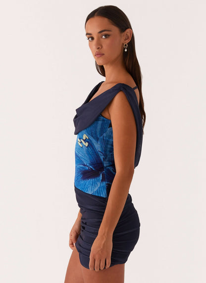 Side profile of navy mini dress with blue butterfly design and draped shoulder detail