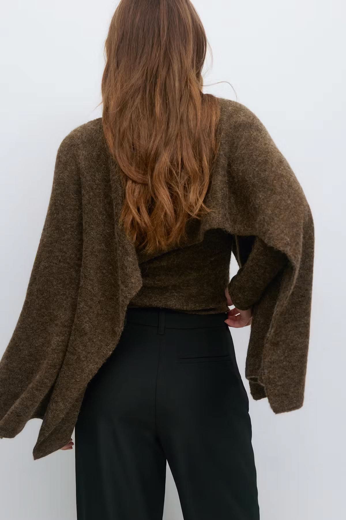 Back view of olive green knitted cape top showing wide draping silhouette