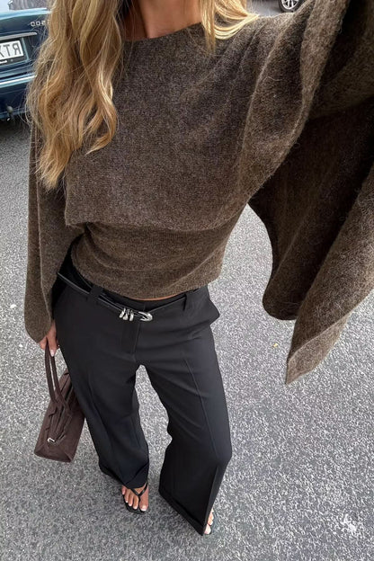 Close-up detail of olive knitted cape fabric texture and flowing sleeve construction