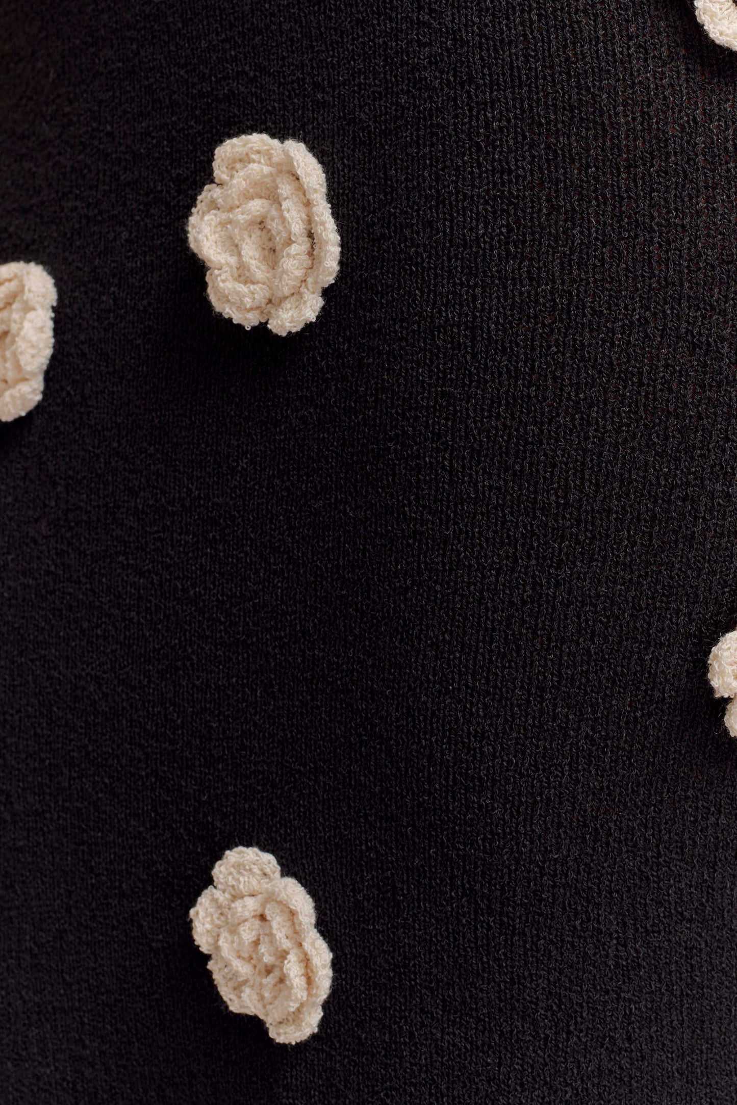 Close-up of cream textured flower appliqué on black fabric
