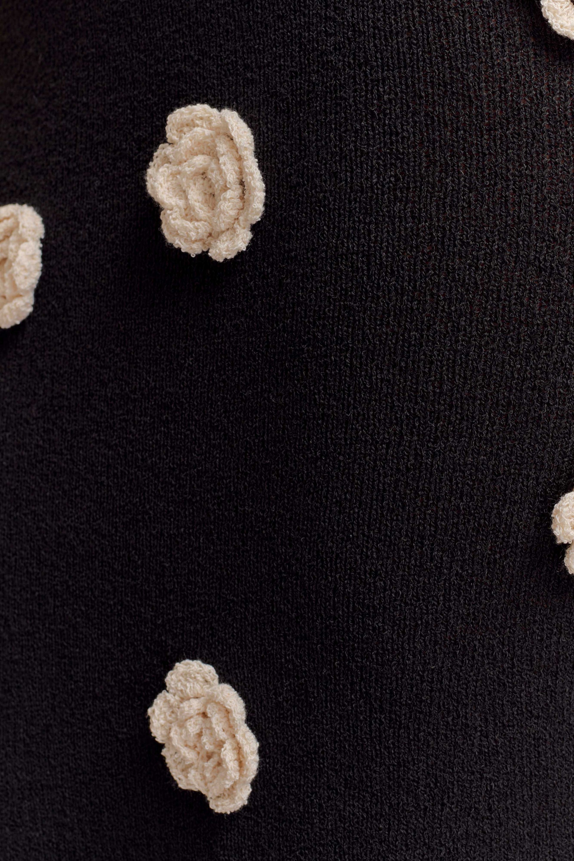 Close-up of cream textured flower appliqué on black fabric