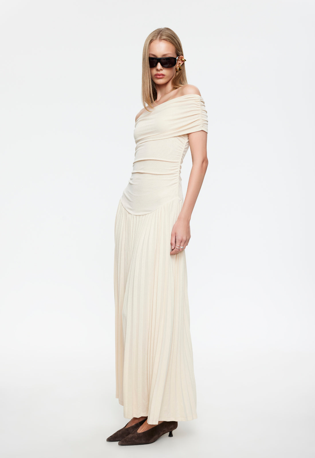 Cream off-shoulder maxi dress front view with fitted ruched top and pleated skirt