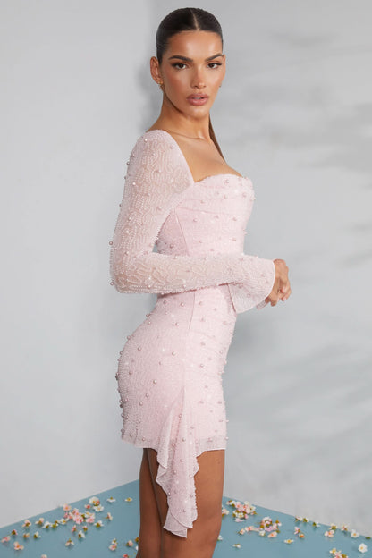 Side profile of blush beaded dress with asymmetrical hemline and long sleeves