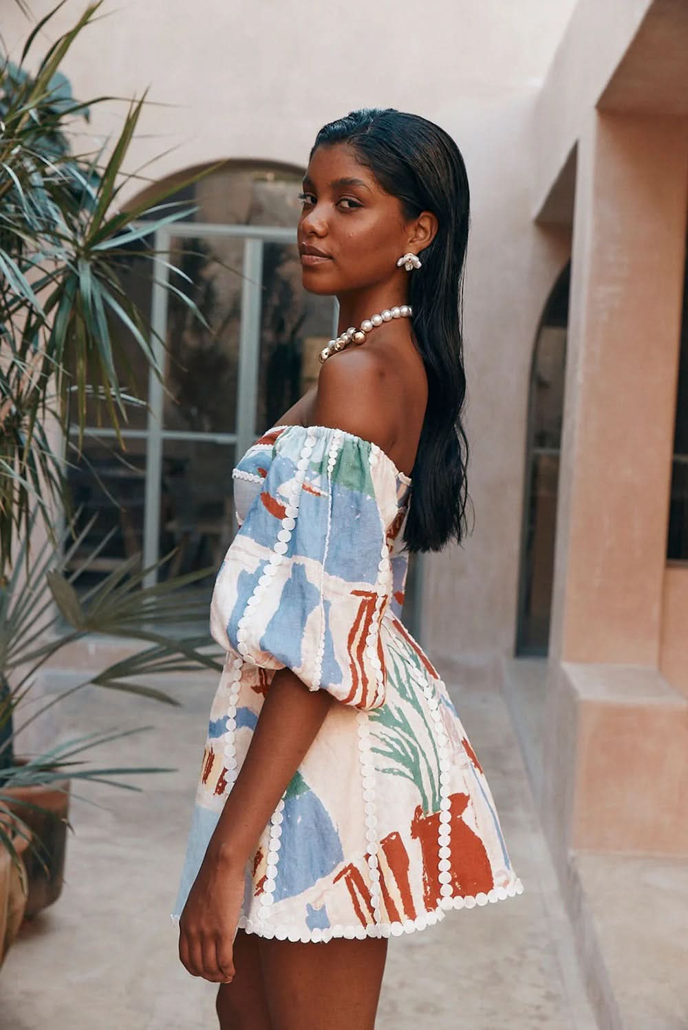 Side view of off-shoulder mini dress with colorful geometric print and pearl trim