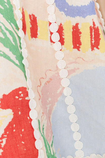 Close-up detail of white pearl trim and red abstract print on dress fabric